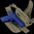 A blue training pistol is placed inside an open Condor Tornado Tactical Leg Holster - Scorpion OCP, featuring khaki camouflage and adjustable straps.